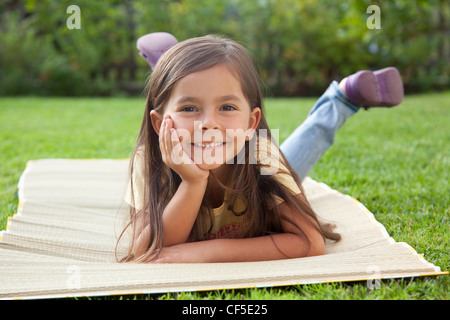 Deutschland, Bayern, Huglfing, Mädchen liegen im Garten, Lächeln, Porträt Stockfoto