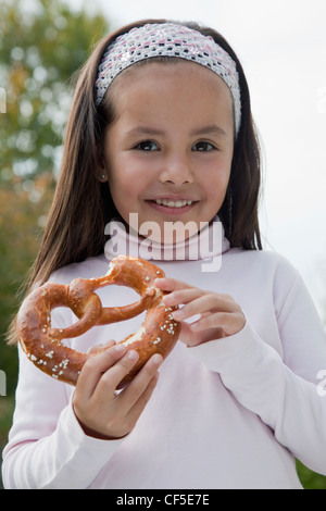 Deutschland, Bayern, Huglfing, Mädchen Holding Brezel im Garten, Lächeln, Porträt Stockfoto