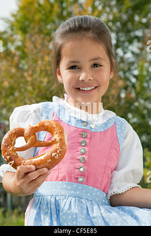 Deutschland, Bayern, Huglfing, Mädchen Holding Brezel im Garten, Lächeln, Porträt Stockfoto