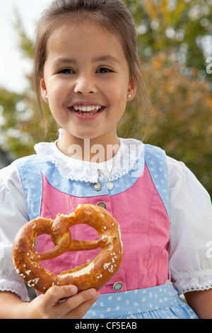 Deutschland, Bayern, Huglfing, Mädchen Holding Brezel im Garten, Lächeln, Porträt Stockfoto