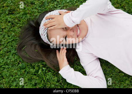 Deutschland, Bayern, Huglfing, Mädchen liegen auf dem Rasen im Garten, Lächeln, Porträt Stockfoto