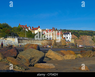 Blick über große Felsbrocken am Strand in Richtung Fischerdorf Dorf von Robin Hoods Bay, der belebtesten Schmuggel-Gemeinschaft auf den Yor Stockfoto