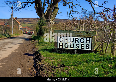 Stein-Schild außerhalb der Kirche die Häuser des Dorfes in Farndale. Stockfoto