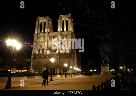 Notre Dame beleuchtet in der Nacht mit paar in Umarmung im Vordergrund Stockfoto