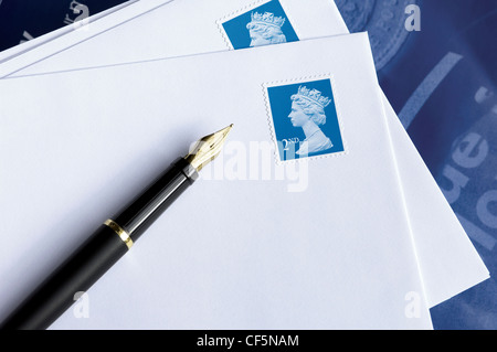 Ein Stillleben mit einem Füllfederhalter ruht auf weiße Umschläge mit zweiter Klasse britische Briefmarken. Stockfoto