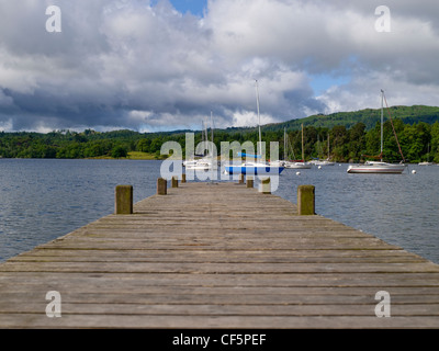 Blick entlang einem Holzsteg in Richtung Boote vertäut am Lake Windermere am Waterhead. Stockfoto