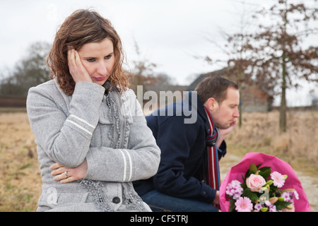 Verärgert Frau sitzend auf Bank mit Mann denken Stockfoto