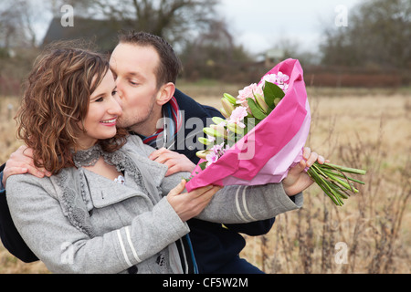 Liebevollen Mann küsst Frau Strauß mit gedrückter Stockfoto