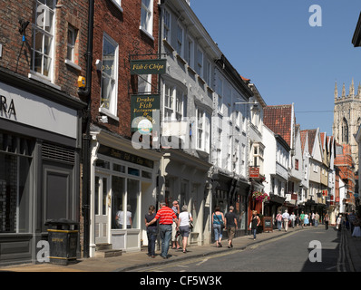 Geschäfte und Restaurants in niedrigen Petergate und die West-Turm des York Minster. Stockfoto