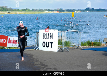 Ein Triathlet verlassen des Wassers und laufen in Richtung der Wechselzone am Eton Dorney, Rudern, Rudern Paralympischen Austragungsort einer Stockfoto