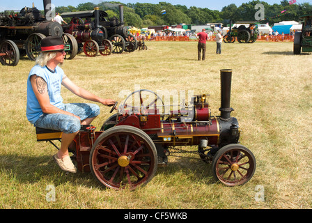 Ein Mann sitzt auf einem Miniatur-Dampftraktor auf der Ringmer Dampf & Country Show. Stockfoto