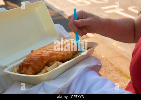 Eine Nahaufnahme einer Frau Essen Fisch und Chips aus einem Fach auf Morecambe Meer. Stockfoto