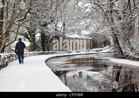 Ein Mann zu Fuß entlang einer Schnee bedeckten Leinpfad von Huddersfield Narrow Canal. Stockfoto