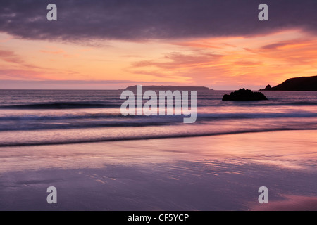 Ein bunten Himmel bei Sonnenuntergang spiegelt sich im nassen Sand am Strand von Marloes Sands. Stockfoto