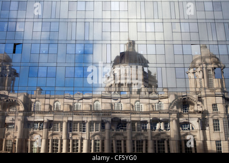 Der Hafen von Liverpool Gebäude spiegelt sich in der Glasverkleidung eines modernen Neubaus. Stockfoto