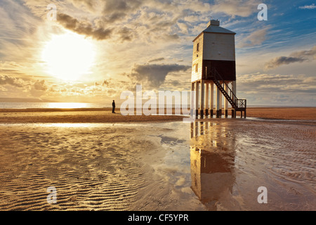 Ein Mann steht am Strand, Blick auf Burnham-on-Sea niedrigen Leuchtturm, erbaut von Joseph Nelson im Jahr 1832. Stockfoto