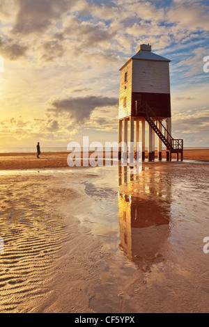 Ein Mann steht am Strand, Blick auf Burnham-on-Sea niedrigen Leuchtturm, erbaut von Joseph Nelson im Jahr 1832. Stockfoto