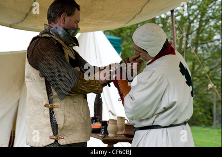 Ein Ritter für die Schlacht bei einem mittelalterlichen Reenactment an Hedingham Castle vorbereitet. Stockfoto