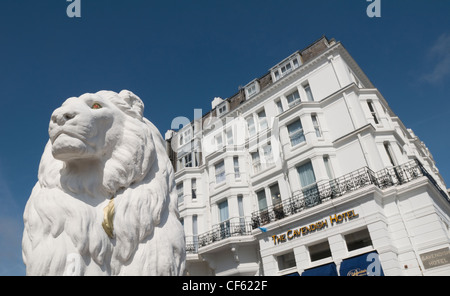 Das Cavendish Hotel am Strand von Eastbourne mit einem steinernen Löwen aus einem benachbarten Hotel im Vordergrund. Stockfoto