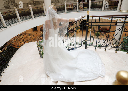 Braut im schönen Hochzeitskleid steht auf breite Treppe, Sicht nach hinten. Stockfoto