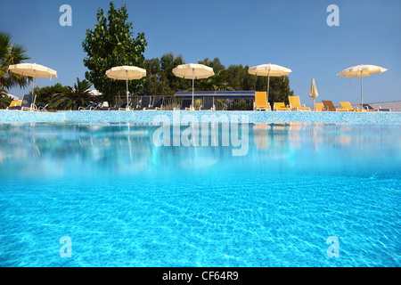 Pool ist unter offenen Himmel eingelegten Kachel am Rande angelegt die Liegestühle mit Sonnenschirmen, unter Wasser eine halbe Foto stehen Stockfoto