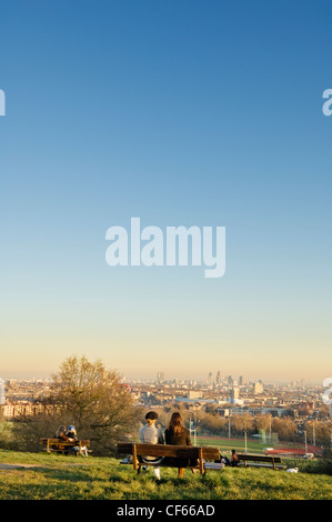Zwei Frauen sitzen auf einer Bank am Parliament Hill mit Blick auf die Skyline der City of London. Stockfoto