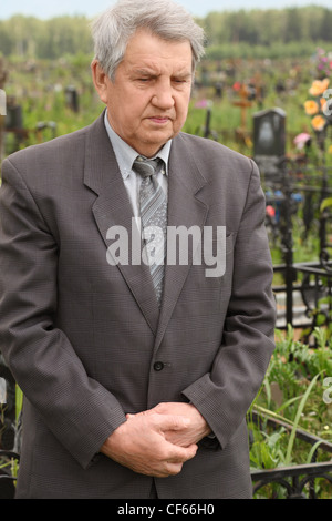 alten traurig Senior im grauen Anzug stehen am Friedhof und blickte, Sommer Stockfoto