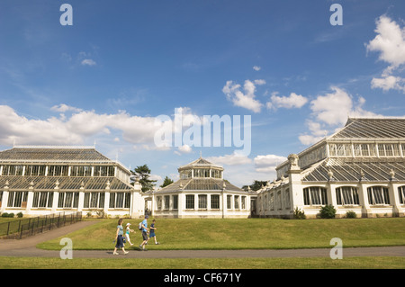 Eine Familie, vorbei an den gemäßigten Haus, größte erhaltene viktorianische Gewächshaus der Welt, in Kew Gardens. Stockfoto