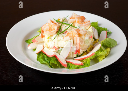 Salat mit Garnelen, Krebsfleisch, Gurken, Äpfel, Kartoffeln, Kopfsalat, Mais, Eiern und Mayonnaise Stockfoto