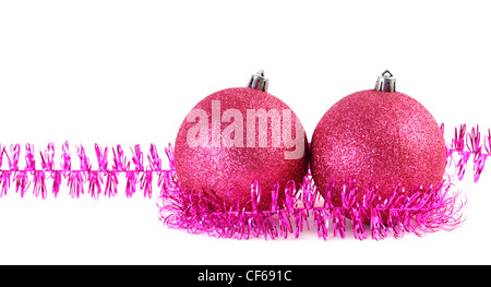 Zwei rote Christbaumkugeln umgeben von lila Lametta isoliert auf weiss Stockfoto