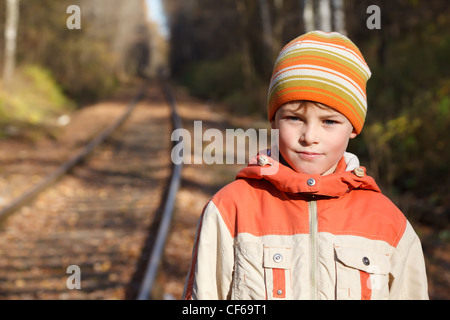 Porträt des jungen Herbst sonnige Tag am Bahnhof. Er ist in Jacke und Mütze bekleidet. Stockfoto