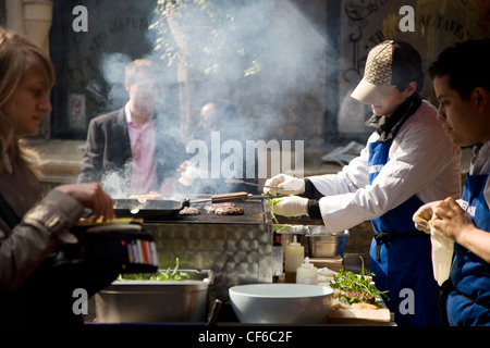 Kunden sehen wie Burger auf einem Backblech im Borough Market gestellt werden. Stockfoto