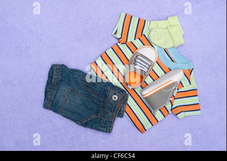 Eine neue Reihe von Baby-Kleidung auf eine lila Decke Stockfoto