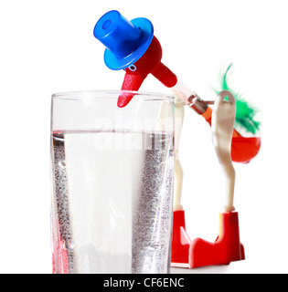 Roter Spielzeug in blauen Hut taucht durch große Schnabel ins Wasser aus transparentem Glas Stockfoto