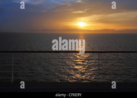 Sonnenuntergang über dem Wasser. Blick vom Deck des Kreuzfahrtschiffes. Schiene im unscharf. Stockfoto