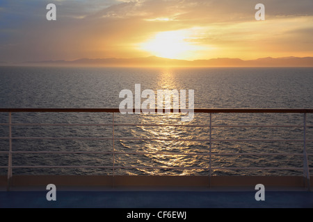 Blick vom Deck des Kreuzfahrtschiffes. Sonnenuntergang über dem Wasser. Schiene im unscharf. Stockfoto