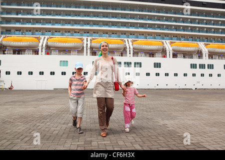 Mutter, Tochter und Sohn wandern im Dock und halten für Hände, große Kreuzfahrtschiff auf Hintergrund Stockfoto