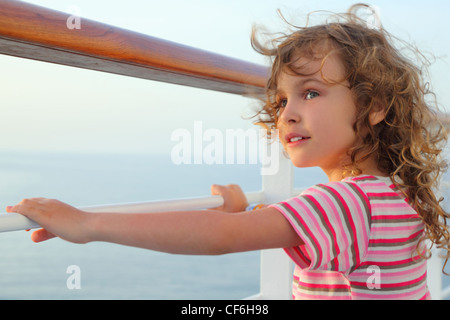 Curl Mädchen stehen auf Cruise Liner Deck, die Hände auf der Schiene, halber Körper nach links Stockfoto