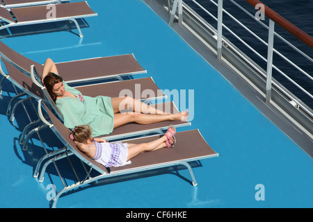 Mutter mit Tochter liegt auf Liegestuhl am oberen Deck des Kreuzfahrtschiffes Stockfoto