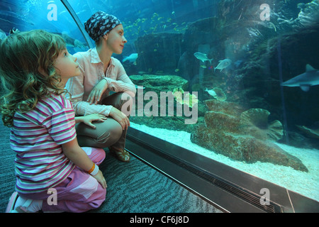 Mutter und Tochter sitzen am Boden im Unterwasser-Aquarium-Tunnel, Weitwinkel Stockfoto