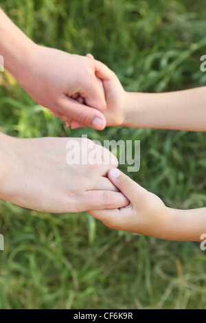 Nahaufnahme von Mutter und Sohn Hände halten einander, grasgrün, vertikale, flache Schärfentiefe Stockfoto