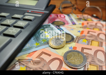 Konzeptbild mit Banknoten und Münzen in Euro-Währung und Rechner zur Bankenkrise in Ländern der Europäischen Union zu veranschaulichen Stockfoto