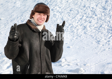 Studentin steht auf Schnee im Winter und Zeigefinger nach vorne zeigt Stockfoto