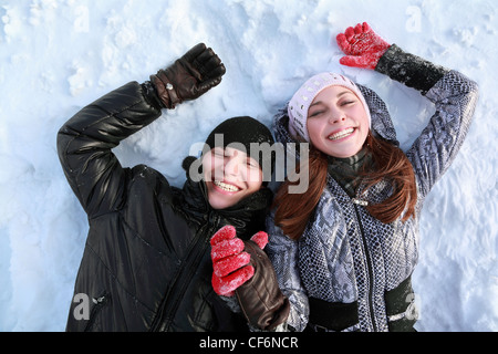 Zwei liebenden Menschen Lügen auf im Winter auf Schnee halten Hände und Lächeln