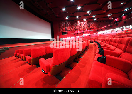 Blick vom Treppen auf Reihen von bequemen roten Sesseln in leuchten rote Zimmer Kino Stockfoto