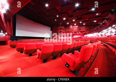 Blick vom Treppen auf Bildschirm und komfortablen roten Stuhlreihen im leuchten rote Zimmer Kino Stockfoto