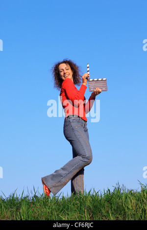 Mädchen auf Wiese mit grünen Rasen gegen blauen Himmel steht und hält die Klappe Stockfoto