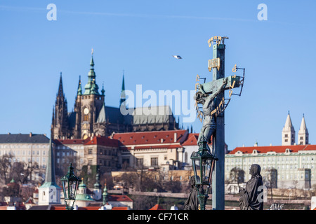Statue von Jesus Christus am Kreuz auf der Karlsbrücke (Karlovski Most), Old Town, Prag, Tschechische Republik mit St Vitus Cathedral Stockfoto