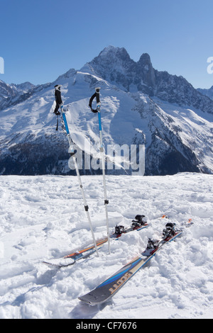 Skier und Skistöcke auf Schnee mit Aiguilles Verte und Les Drus im Hintergrund Stockfoto