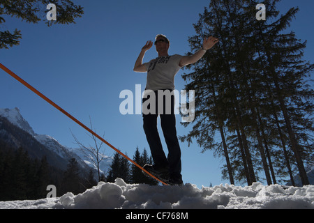 Mann zu Fuß auf einer Slackline im Tal von Chamonix mit alpinen Bergen im Hintergrund. Stockfoto